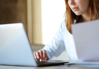 Woman working online with papers