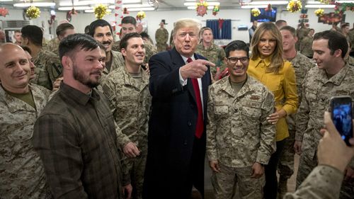 President Donald Trump and first lady Melania Trump pose for a photograph as they visit members of the military at a dining hall at Al Asad Air Base, Iraq