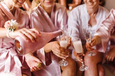 Young bridesmaids clinking with glasses of champagne in hotel room. Closeup photo of cheerful girls celebrating a bachelorette party. Females have toast with wine. Stock image