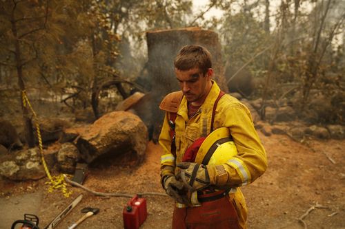 Firefighter Shawn Slack rests after felling trees.