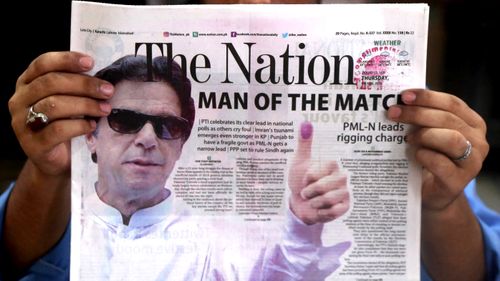 A person reads a Pakistani newspaper with a picture of Imran Khan, head of Pakistan Tehrik-e-Insaf (PTI) political party, on the front page a day after general elections. (AAP)