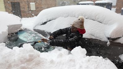 Zaria Black, 24, from Buffalo, clears off her car as snow falls Friday, November 18, 2022, in Buffalo, NY. 