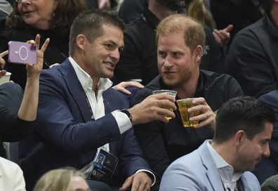 British Prince Harry, right, the Duke of Sussex, drinks beer with retired New Zealand rugby player Richie McCaw while watching the U.S. and Australia play the bronze medal wheelchair rugby match during the 2025 Invictus Games, in Vancouver, on Thursday, Feb. 13, 2025. (Darryl Dyck/The Canadian Press via AP)