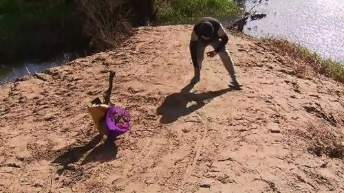 a man writes a message in the sand near where the boys were found