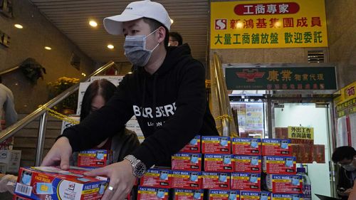 A Hong Kong shop worker puts face masks on display as the coronavirus spreads.