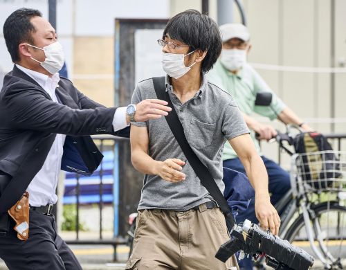 Tetsuya Yamagami, centre, holding a weapon, is detained near the site of gunshots in Nara, western Japan Friday, July 8, 2022. 