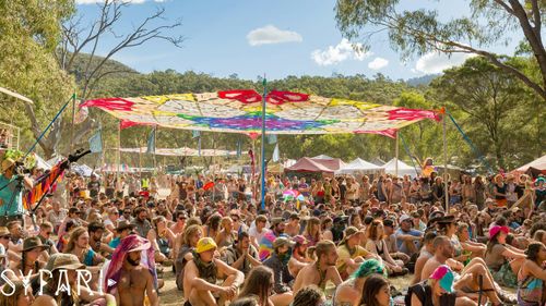 Revellers sit under a shadecloth at NSW musci festival "Pysfari".