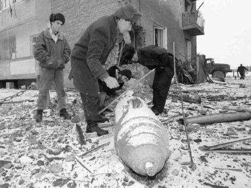Residents in Grozny look at an unexploded Russian bomb.