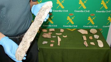 A policeman holds a piece of archaeology recovered by the Spanish Guardia Civil during a joint operation. (AFP)