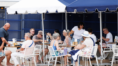 A group of grey-haired people dine at an outdoor cafe.