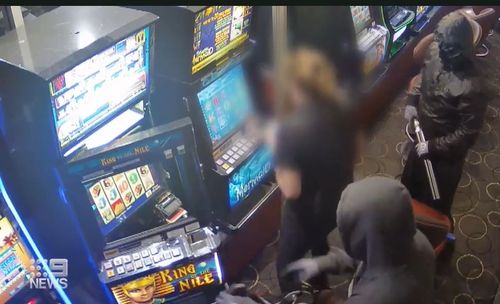 The armed men standing over the worker as she unlocks the gaming machines.