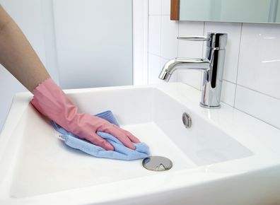 cleaning the washbasin with microfiber cloth and gloves