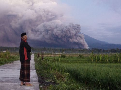 Un homme regarde le mont Semeru libérer des matériaux volcaniques lors d'une éruption dimanche, à Lumajang, dans l'est de Java, en Indonésie.