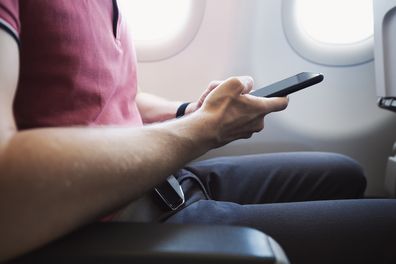 Hands holding smart phone in airplane. Passenger using internet connection during flight.