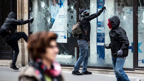 Protesters attack a window of a bank as public workers unions demonstrate in Paris, France. (AAP)