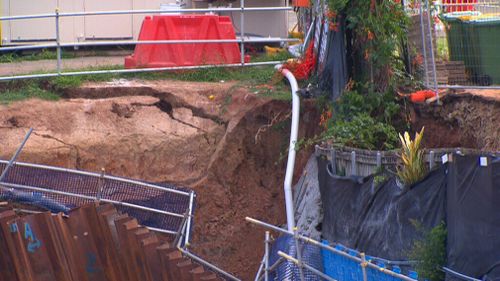 The collapsed retaining wall has dragged down a footpath and a carport. (9NEWS)