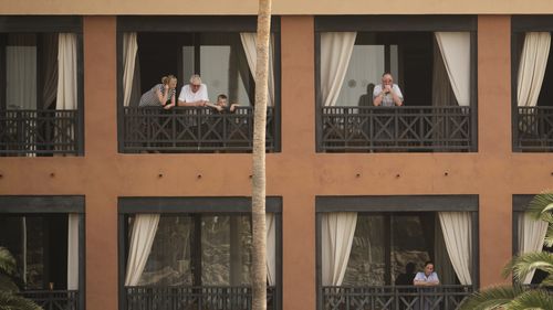 People stand on their balconies of the H10 Costa Adeje Palace after the hotel went into lockdown following two guests testing positive for coronavirus.