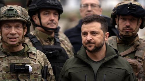 Ukrainian President Volodymyr Zelenskyy poses for a photo with soldiers after attending a national flag ceremony in liberated Izium.
