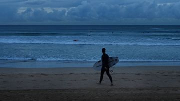 A surfer walks towards the water on Manly beach. And residents across Sydney are being warned not to pack away the umbrellas just yet; The Bureau of Meteorology (BoM) said the city could be hit with 20-40mm of rain today.