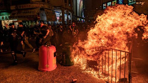 Pro-democracy protesters run behind a burning barricade after police charged toward them during a demonstration in Mongkok district on October 1, 2019 in Hong Kong.