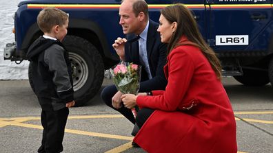 HOLYHEAD, WALES - SEPTEMBER 27: Prince William, Prince of Wales (C) gestures as his wife Catherine, Princess of Wales is presented with a posy of flowers by four-year-old Theo Crompton during their visit to the RNLI (Royal National Lifeboat Institution) Holyhead Lifeboat Station, during a visit to Wales on September 27, 2022 in Holyhead, Wales 