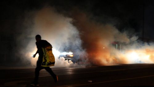 A protester flees tear gas clouds. (AAP)