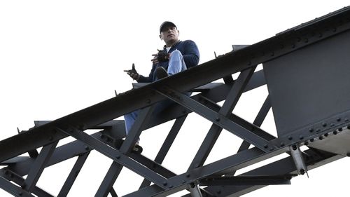 The man was sitting precariously on the bridge beams with police for around five hours. (AAP)