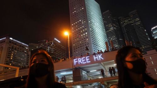 People stand on a carpark lot watch medical volunteers and firemen attend a rally in Hong Kong.