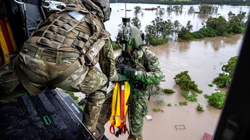 Army Warrant Officer Class Two Benjamin Dwyer from the School of Army Aviation prepares to conduct a rescue by winch of a community member from an MRH-90 Taipan, over Lismore.