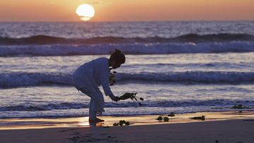 A woman places flowers on beach in Iwaki city, Fukushima prefecture on Saturday, March 11, 2023. 