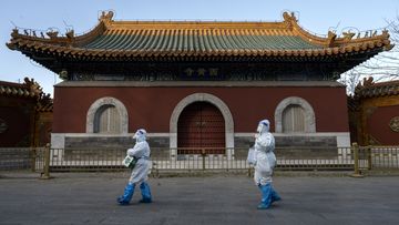 Epidemic control workers wear PPE as they walk by the Huangsi Temple on their way to perform nucleic acid tests on people under lockdown or health monitoring for COVID-19 on December 3, 2022 in Beijing, China. (Photo by Kevin Frayer/Getty Images)