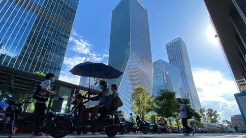 Residents pass near the headquarters for Evergrande in Shenzhen in southern China.