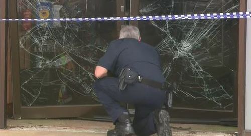 A detective examines the damage at the scene of the ram-raid.