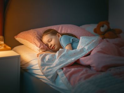 Adorable little child is sleeping in the bed.