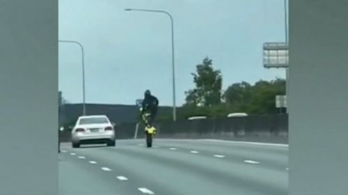 The man was captured performing one-handed wheelies while standing on his bike. 