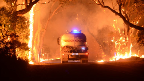 A truck weaves its way through the fire at Tarrara Lane in Bradbury. 