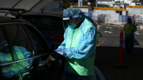 Registered Nurse Veronica Wakeford conducts a COVID-19 swab test as large crowds queue at a Bondi Beach drive-through testing clinic