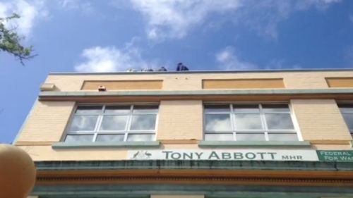 The four protesters are sitting at the edge of the roof. (Grant Williams, ACA)