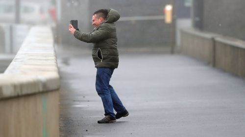 A man battles harsh winds to take a photograph. (AP)