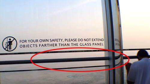 The viewing platform on the 148th floor of the Burj Khalifa, now with a bar in the gap and warning sign on the glass barrier. (YouTube)
