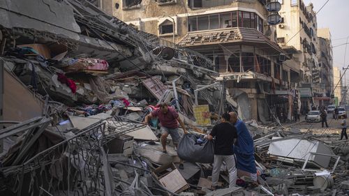 Palestinians scour the debris from the rubble of a building after it was struck by an Israeli airstrike, in Gaza City.