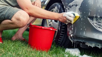 Young male washing car with a sponge and foam