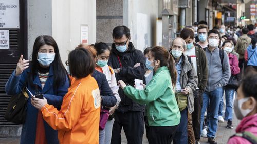 Members of the public wait in line outside a community vaccination centre in Hong Kong.