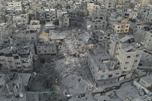 2023 年 10 月 27 日星期五，加沙地带汗尤尼斯难民营，巴勒斯坦人在以色列空袭后检查房屋废墟。