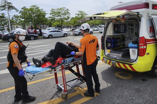 Спасатели несут пассажира на носилках в машину скорой помощи в международном аэропорту Тэгу в Тэгу, Южная Корея, пятница, 26 мая 2023 года.  