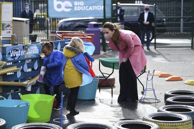 Kate Middleton, Duchess of Cambridge talks with a child in the water area of the playground during a visit with Prince William to School21, a school in east London, Thursday March 11, 2021