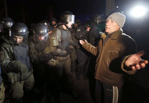 Protesters, who planned to stop buses carrying passengers evacuated from the Chinese city of Wuhan, speak to Ukrainian riot police.