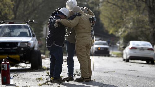 A team from Summit Energy say a prayer together before investigating a burst gas line in Cammack Village after a tornado swept through the area Friday, March 31, 2023 in Little Rock, Ark. 