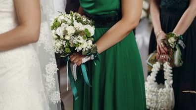 Bridesmaid in green dress standing behind bride.