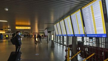 A traveller wearing a face mask checks the flight departures at Schiphol Airport, near Amsterdam, Netherlands (Photo: December 18, 2020)